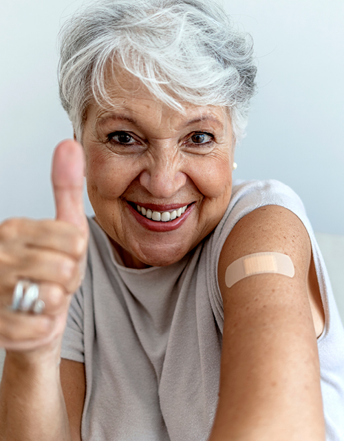 Cropped shot of a smile senior woman 70s after receiving the coronavirus covid-19 vaccine. Old aged woman posing with an adhesive COVID-19 and adhesive bandage on her upper arm.